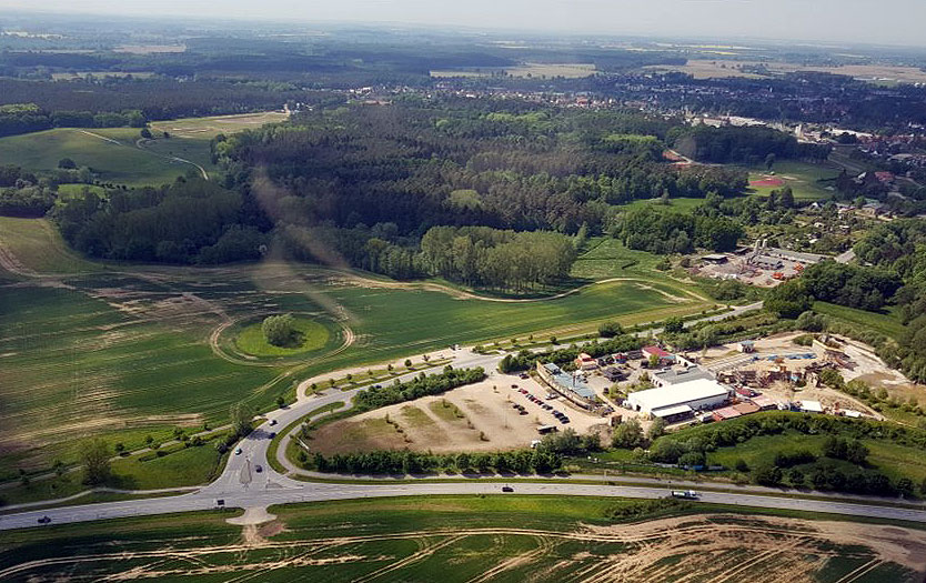 Das Piraten Action-OpenAir-Theater Grevesmühlen bietet aus der Luft betrachtet eine beeindruckende, detailgetreu gestaltete Kulisse. Luftaufnahme eines ländlichen Gebiets mit Feldern, Wäldern und einem kleinen Gebäude in der Mitte.