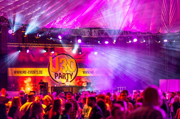 Bunte Lichter und eine fröhliche Menschenmenge bei einer U30-Party.